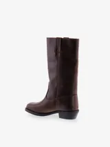 Bota de caña media color marrón oscuro, estilo vaquero, confeccionada en cuero. Presenta punta cuadrada y taco bajo y ancho.