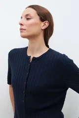 Cardigan gris melange de tejido de punto con diseño texturizado, manga corta y cierre frontal con botones.