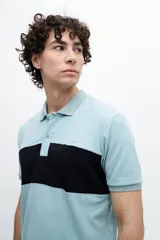 Chomba de piqué verde con una franja horizontal negra en el pecho.