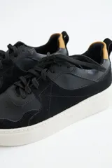 Zapatillas de gamuza verde oliva con cordones marrones y suela de goma color crema.