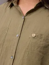 Camisa de algodón y lino color crudo, con cuello camisero, cierre frontal de botones, bolsillos aplicados en el pecho y mangas largas con presilla para arremangar.