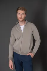 Campera de algodón color beige con cierre frontal, cuello alto y bolsillos laterales.