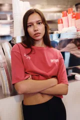 Remera de corte oversize con efecto lavado, color rojo, cuello redondo y manga corta con hombro caído. Presenta un estampado pequeño en el pecho con el logo de la marca y un dibujo lineal de una taza de café.