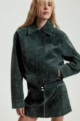 Cazadora de ante color verde oscuro, con cuello solapa, cierre frontal con cremallera oculta y botones a presión, bolsillos laterales con cremallera, manga larga con cremallera en puños y bajo elástico.