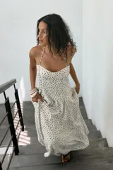 Vestido midi de corte fluido con escote halter y lazada ajustable al cuello. Presenta un diseño con estampado de lunares y falda con volumen.