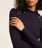 Blusa azul marino de mangas largas, confeccionada en rib con viscosa, cuello alto y perlas artificiales aplicadas en los hombros.