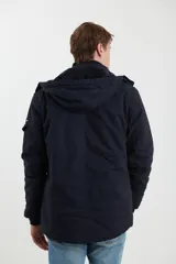 Campera de abrigo estilo parka, color verde militar, con capucha desmontable, cierre frontal con botones y múltiples bolsillos funcionales en pecho, cintura y manga.