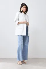 Blazer de corte recto y diseño minimalista, color blanco, con solapas clásicas, bolsillos frontales con solapa y mangas tres cuartos con detalle de botones.