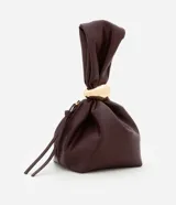 Bolso tipo bucket pequeño color marrón oscuro, confeccionado en material sintético con poliéster certificado. Tiene correa de mano y detalle de metal dorado.