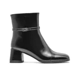 Bota de vestir Korium modelo Sandy, de caña media en cuero negro con acabado brillante. Presenta una tira decorativa delgada con hebilla metálica alrededor del tobillo y un taco cuadrado de altura media.