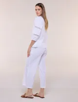 Pantalón crop de lino y algodón color blanco, con calce holgado, pierna ancha de corte recto y cintura elástica. Presenta bolsillos laterales y detalle de puntilla aplicada en el frente.