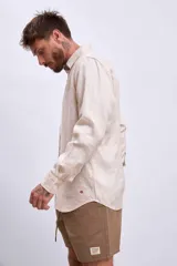 Camisa de lino color crudo, de corte recto, con cuello clásico y mangas largas.