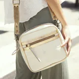 Bandolera de cuero vacuno color blanco con textura croco y detalles dorados. Tiene correa larga ajustable y removible, bolsillo externo con cierre y forro interior con bolsillo con cierre.