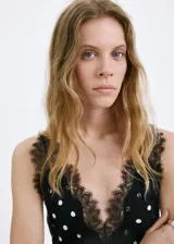 Vestido midi negro con estampado de lunares blancos, escote en pico con detalle de encaje, tirantes y diseño fluido de corte recto.