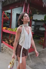 Top negro de tejido de punto con escote halter y lazada frontal ajustable. Presenta un diseño ajustado al cuerpo.