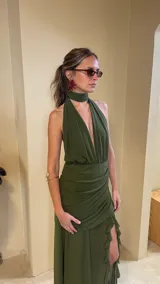 Vestido largo de microtul color verde militar, con escote profundo halter, cuello choker incorporado, frunces en la zona de la cintura y falda larga con tajo y volados.
