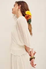 Camisa blanca de manga larga abullonada, con cuerpo de red transparente con bordados florales en tono crudo y aplique de flor grande fucsia en el hombro.