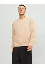 Buzo color beige de manga larga y cuello redondo, con calce relajado y hombros caídos.