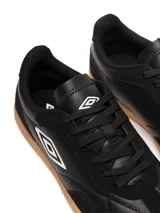 Championes Umbro modelo Track, color negro, con suela de goma color caramelo. Presenta el logo Umbro en el lateral en color blanco.