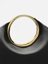 Bolso mini tipo clutch color negro, de cuero napa, con forma orgánica y asa de aro dorada integrada.