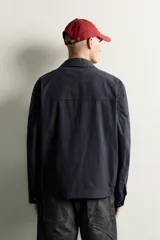 Cazadora regular fit de diseño ligero con patrón a cuadros en tonos azul marino y negro, confeccionada con mezcla de algodón y lino. Cuenta con cuello solapa, manga larga con puños abotonados, bolsillos de vivo en la cadera, detalles elásticos en los laterales del bajo y cierre frontal con cremallera de doble dirección.