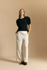 Remera blanca de cuello redondo con mangas cortas abullonadas y detalle de nudo en los puños.