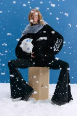 Sweater oversize de tejido de punto grueso en color negro, con cuello redondo y diseño de estampado gráfico en el pecho y en una de las mangas. Presenta un acabado desgastado que le otorga un estilo vintage.