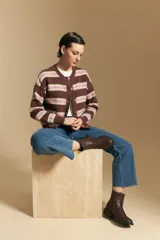 Cardigan de punto con diseño de rayas horizontales en tonos marrón, rosa y beige. Presenta cuello redondo, cierre frontal con botones y mangas largas con puños acanalados.