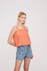 Musculosa blanca con breteles finos y detalles de puntilla.