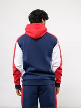 Campera deportiva Umbro del Club Nacional de Football, con cierre frontal, capucha ajustable con cordones y diseño en bloques de color azul, celeste y blanco. Presenta el logo de la marca y el escudo del club bordados en el pecho.