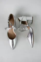 Sandalia de tacón cuadrado color blanco, con diseño de punta fina cerrada y tiras cruzadas ajustables con hebillas metálicas doradas.