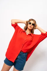 Camisa roja amplia de manga larga con ruedo curvo.