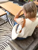 Cartera tipo hobo de cuero color crudo con correa de cuero marrón.