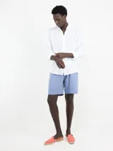 Camisa de hombre blanca, lisa, confeccionada en 100% lino, con cuello italiano, cierre de botones, manga larga con puño simple y logo bordado en el pecho.