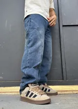 Pantalón de denim azul con diseño balloon y costuras curvas decorativas en las piernas.