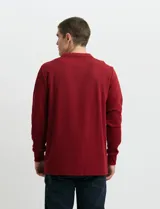 Remera de punto canalé francés con cuello polo, manga larga y cierre frontal de metal con tirador personalizado.
