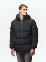 Campera puffer negra con diseño capitoneado, cuello alto y capucha integrada. Cuenta con cierre frontal completo, bolsillos laterales con cierre y puños con ojal para el pulgar.