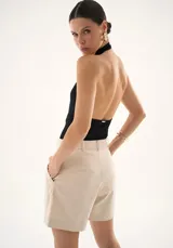 Body negro de corte ajustado con espalda descubierta y cuello halter, confeccionado en tejido elástico con cierre inferior.