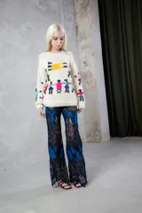Sweater de lana tejido y bordado a mano, de color crudo con diseño de figuras coloridas. Presenta un calce holgado, cuello redondo y mangas largas.