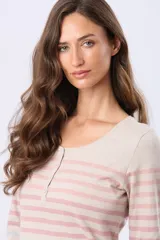 Remera de manga larga con cuello redondo y cierre frontal parcial con botones. Presenta un diseño de rayas horizontales en tonos pastel sobre una base beige, con aberturas laterales en el ruedo.