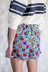 Short unisex de corte holgado con cintura elástica y estampado a cuadros rojos y blancos con dibujos de frutas.