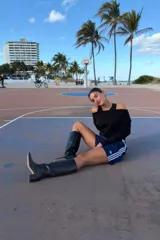 Bota de caña alta confeccionada en cuero negro, con diseño minimalista, punta fina y taco cuadrado de altura media.