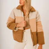 Campera puffer color block en tonos beige, tostado y marrón, con diseño acolchado, cuello alto y cierre frontal con cremallera.