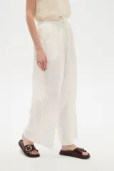 Pantalón de lino blanco, de corte ancho y tiro alto con cintura elástica fruncida y cordón ajustable.