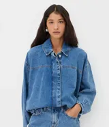 Campera de jean azul estilo balloon, con cuello tradicional, cierre frontal oculto y bajo con elástico.