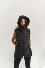 Chaleco negro oversize con capucha forrada en tela gamuzada, cierre metálico YKK, bolsillos laterales y tancas regulables en el ruedo.