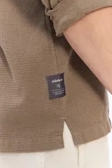 Camisa de manga larga color beige, de tejido texturado con cierre frontal de botones y cuello camisero clásico.
