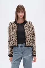 Cardigan de tejido de punto, corto, con estampado animal print en tonos beige y negro. Presenta cuello redondo y ribetes negros en el borde frontal, puños y ruedo.