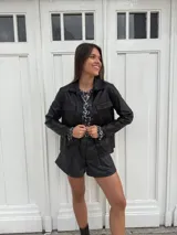 Chaqueta dorada metalizada con cuello camisero, cierre frontal con botones y bolsillos de parche en el pecho.