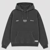 Canguro con capucha y cordones ajustables, de color gris oscuro con efecto lavado. Presenta un bolsillo frontal tipo canguro y estampado gráfico pequeño en el pecho con el logo de la marca.